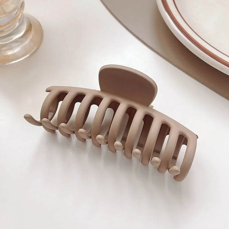 Women’s elegant brown and beige floral geometric hair claw clip on a table, perfect for stylish hairstyles.