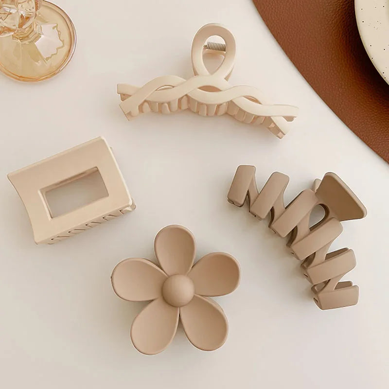Collection of elegant beige hair claw clips in various shapes including floral and geometric designs.